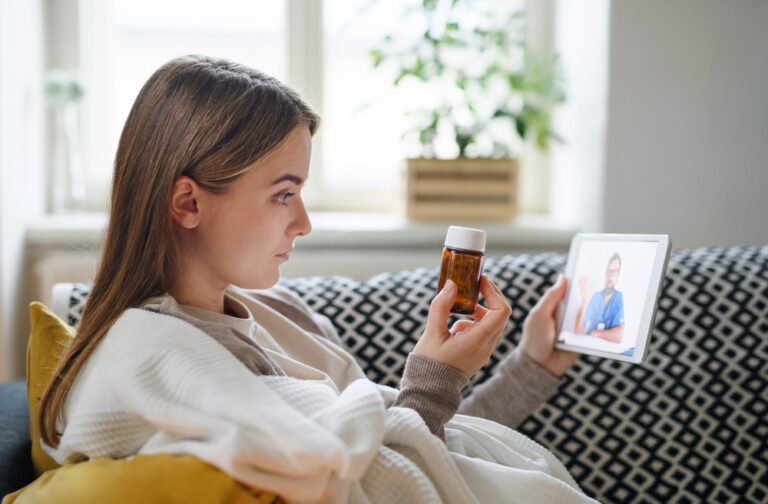 Young woman having video call with doctor on tablet at home, online consultation concept.